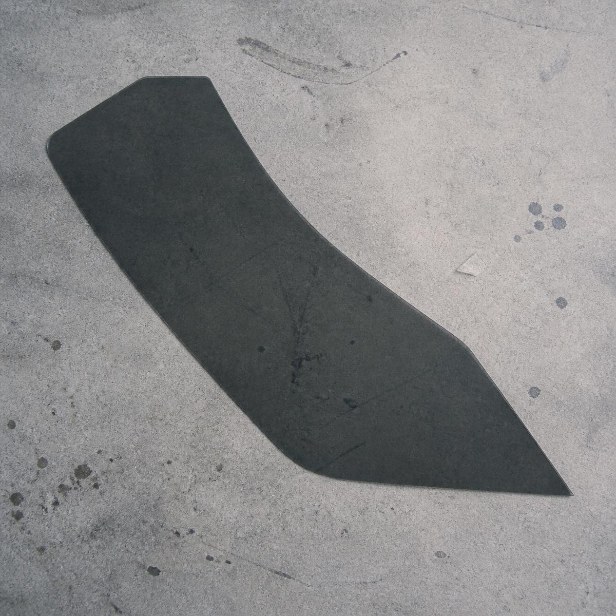 A single precut piece of dark ceramic window tint film on grey concrete.